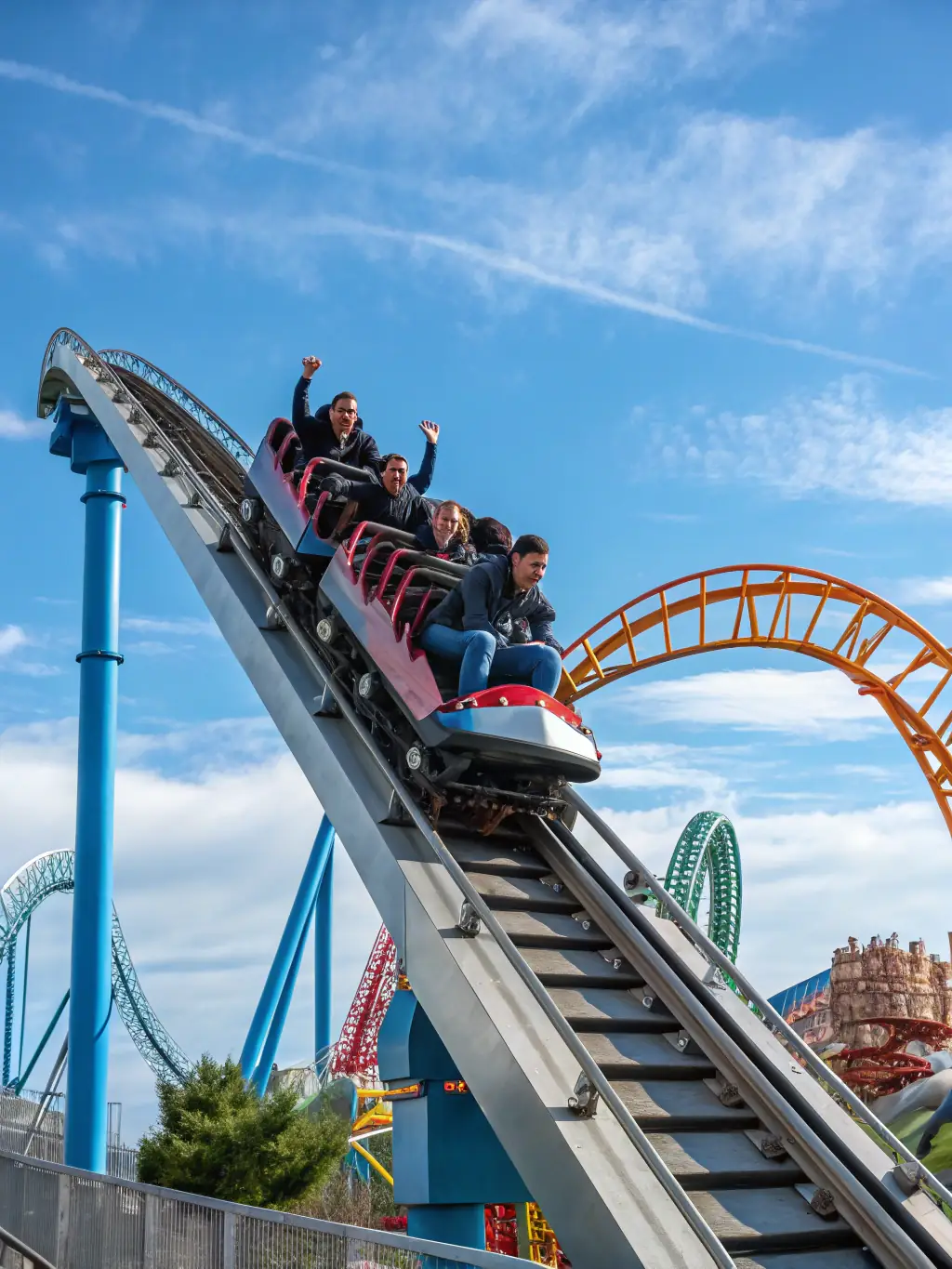 A high-angle, vibrant photograph capturing the Hyperion roller coaster in full operation, showcasing its steep drops and excited riders against a clear blue sky at Energylandia.